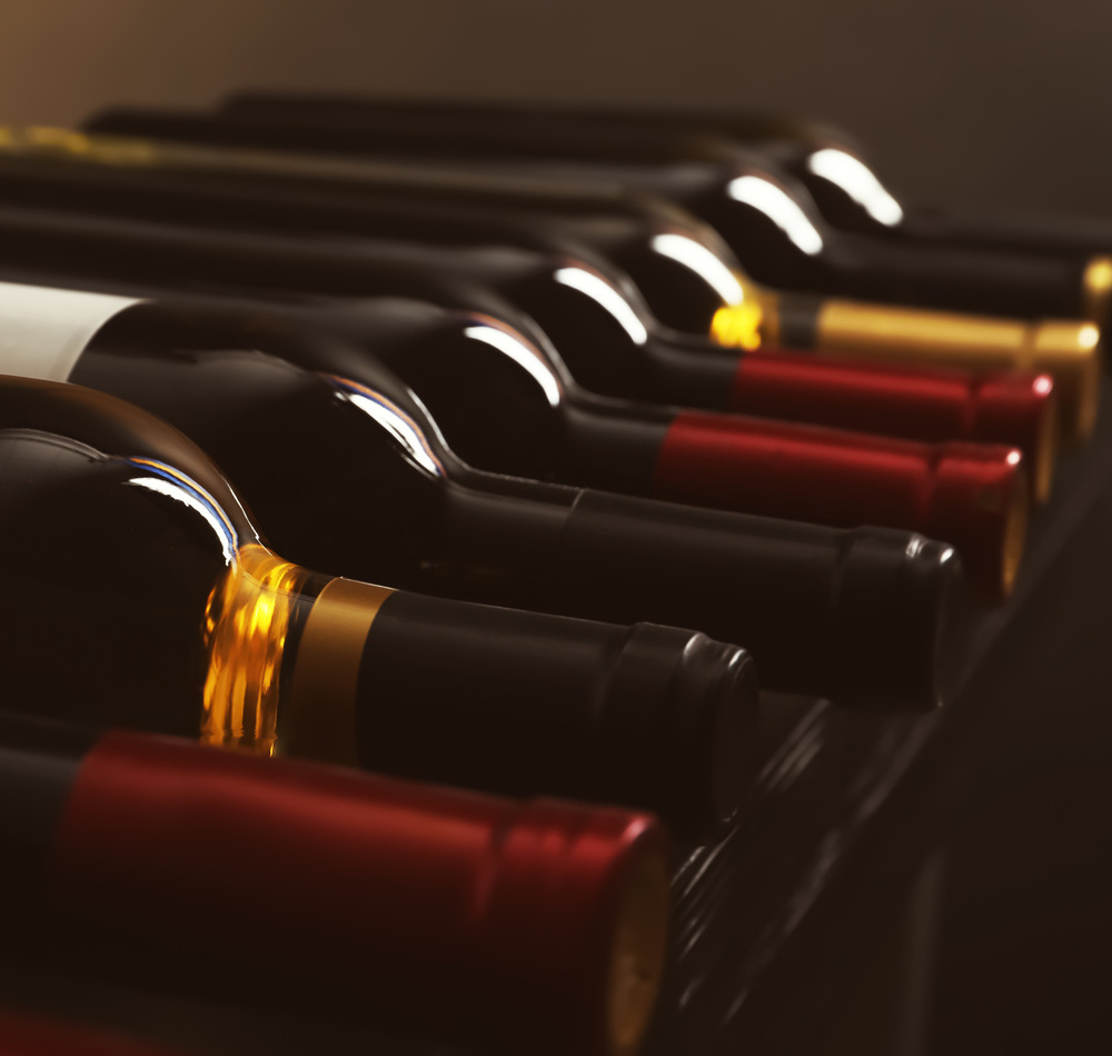 Bottles with delicious wine on shelf, closeup. Professional sommelier